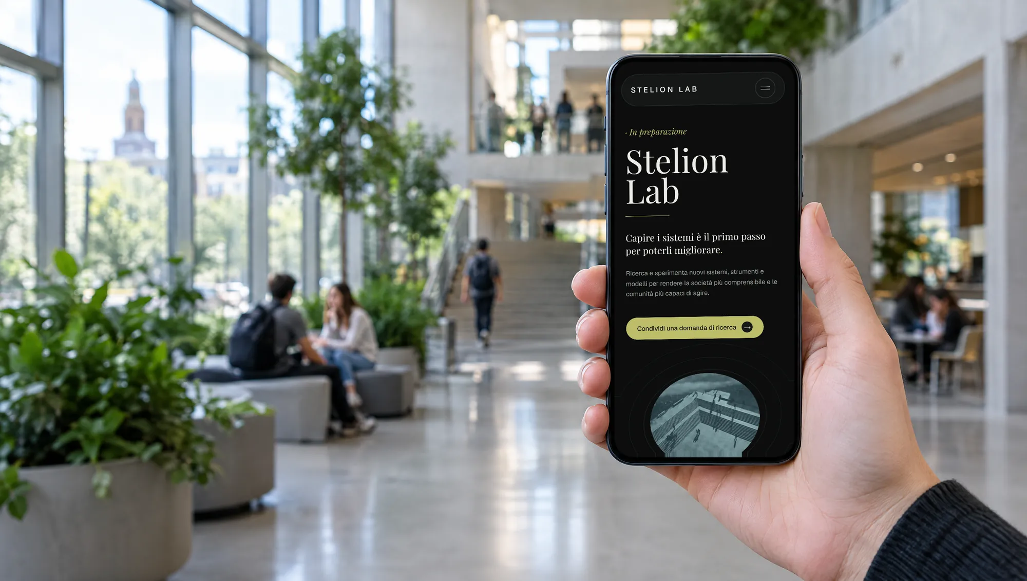 The Stelion Lab website on a phone held up in a university atrium